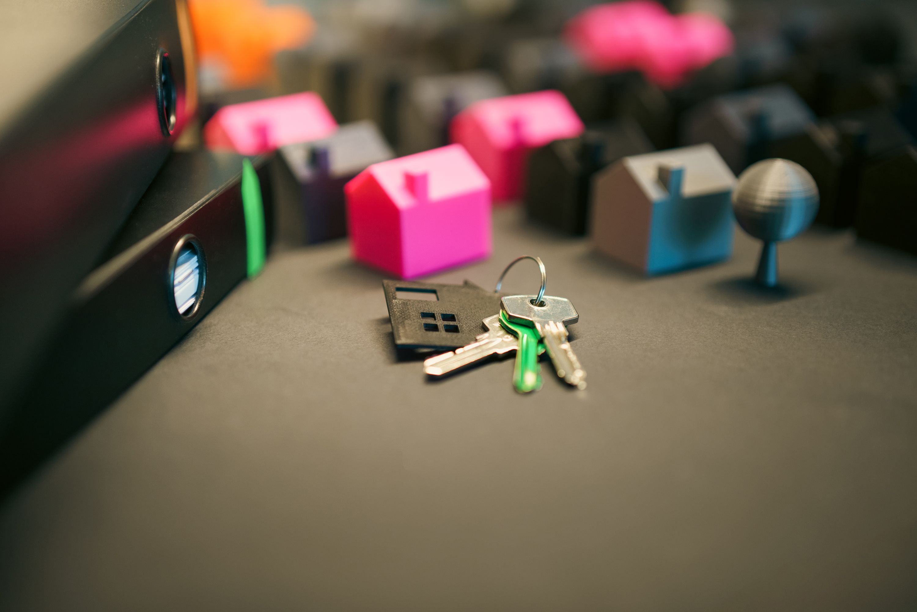 House keys on a desk beside paperwork and a laptop.